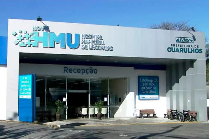 Paciente aguardando atendimento em corredor lotado de hospital público em Guarulhos.