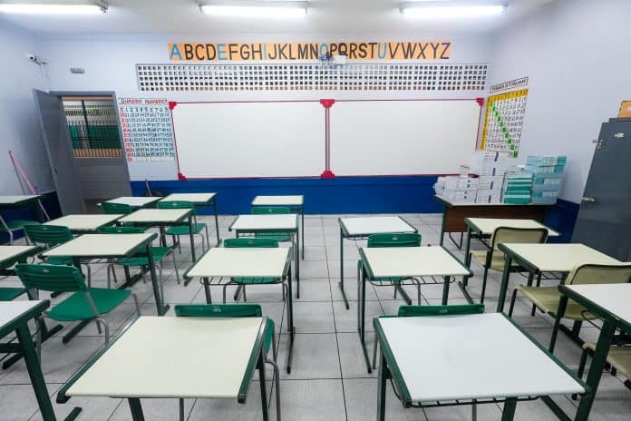 Mães e pais na porta de uma das escolas de Guarulhos conversando sobre o atraso na entrega dos uniformes escolares.