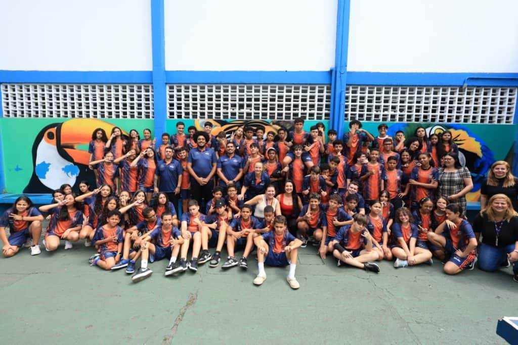 Alunos do projeto Fábrica de Atletas em Guarulhos vestindo os novos uniformes de vôlei e basquete durante cerimônia de entrega oficial.